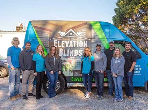 Staff posing for a photo by the company vehicle